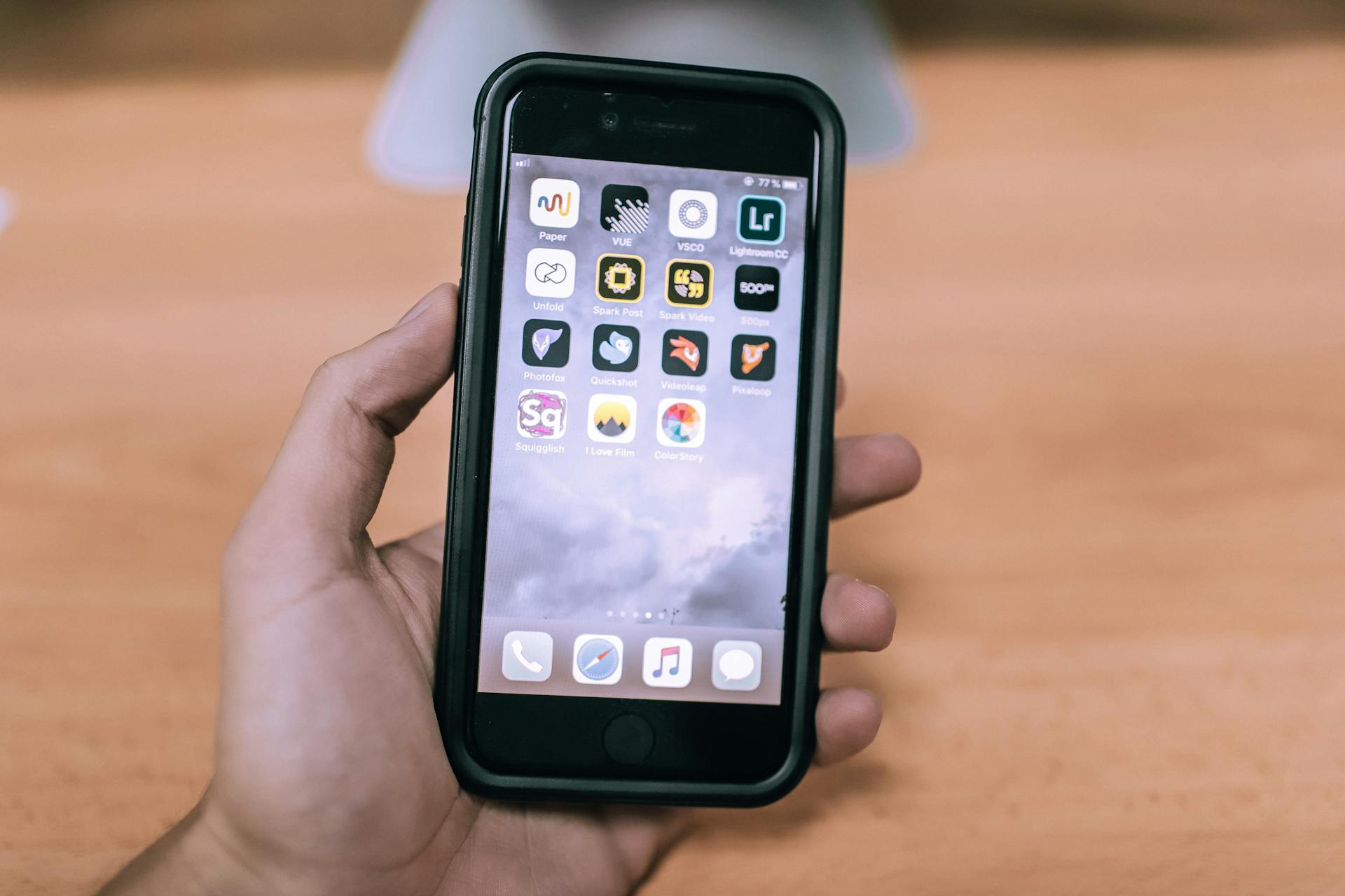 A close-up image of a hand holding a smartphone with various app icons visible on the screen.