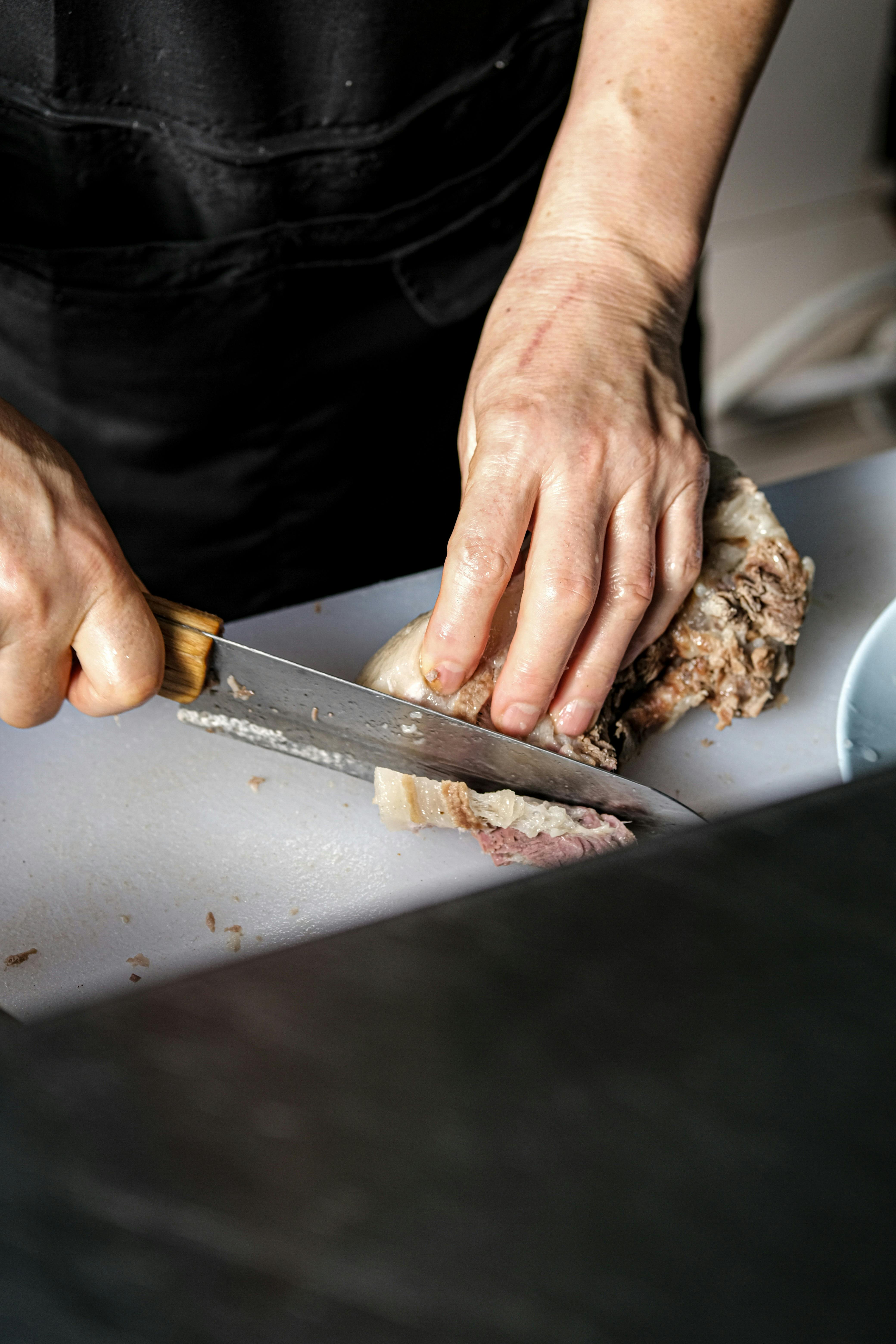 Chef cuts up meat on a cutting board with a sharp knife Stock Photo by  wirestock