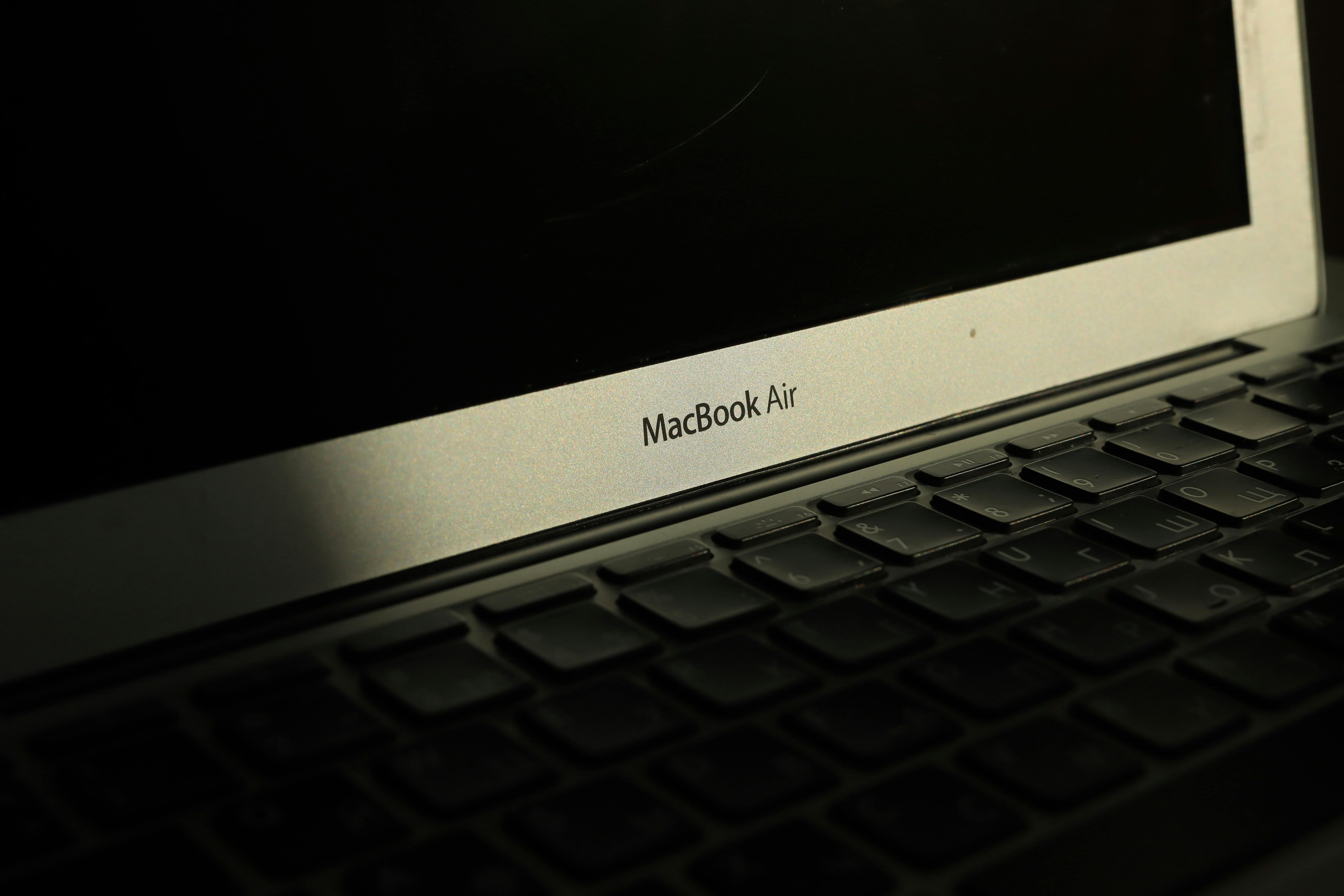 Free Close-up of a sunlit MacBook Air laptop showcasing its keyboard and screen with shadow effects. Stock Photo