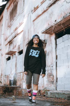 一位穿着街头服饰的年轻女子在城墙旁微笑，散发着时尚气息