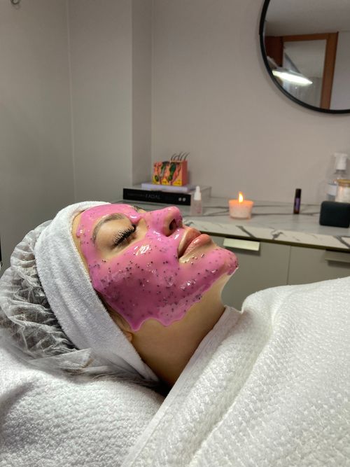 Free Woman enjoying a calming pink face mask spa treatment indoors. Stock Photo