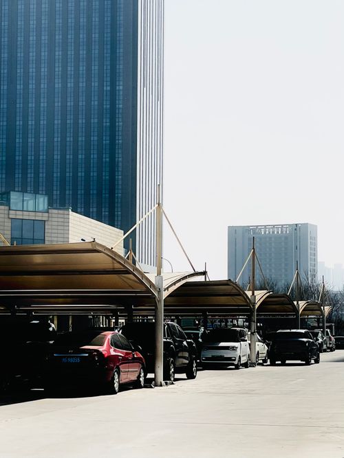 Free A parking lot with covered spaces and tall buildings under bright daylight. Stock Photo