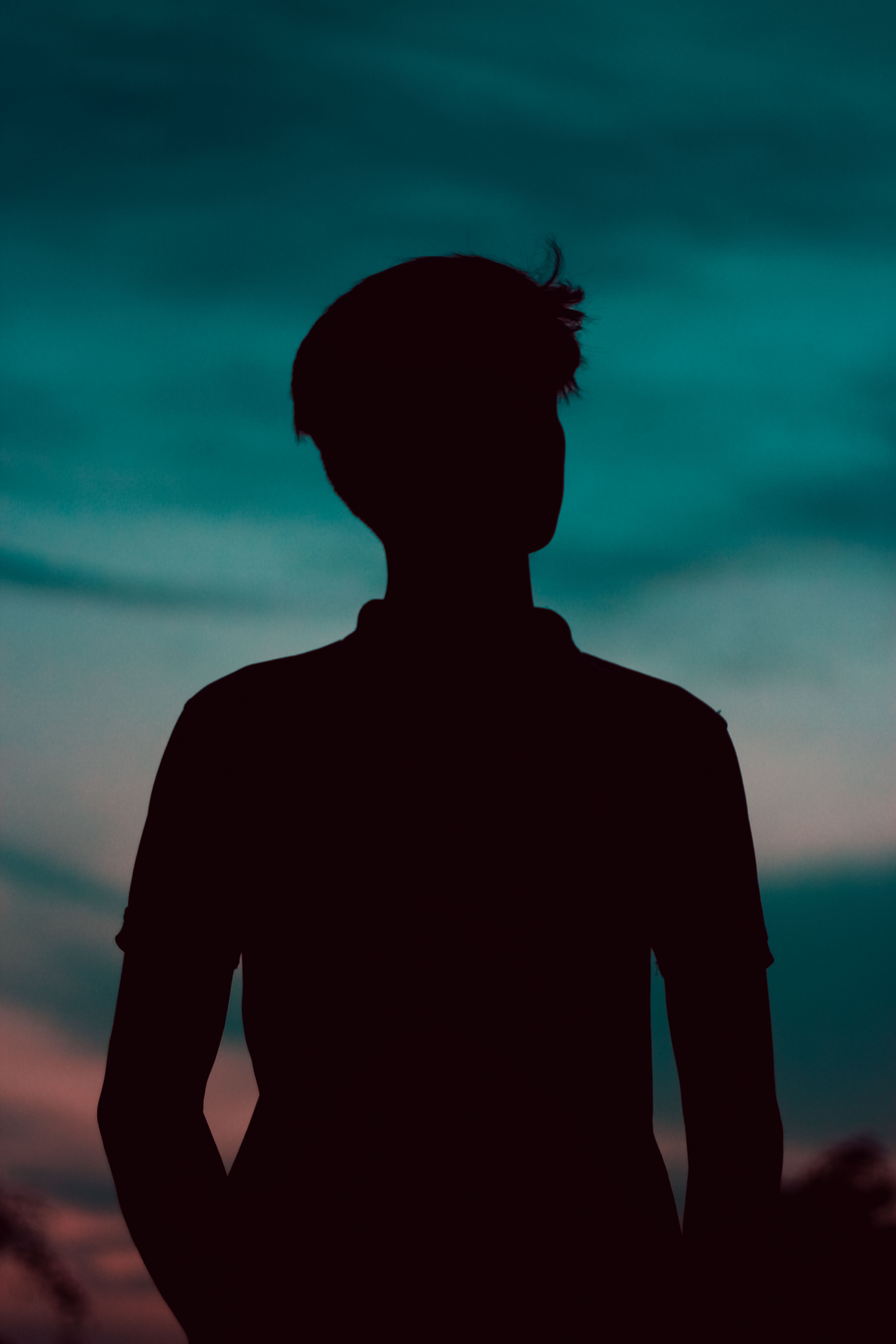 A silhouette of a man standing in front of a sunset · Free Stock Photo