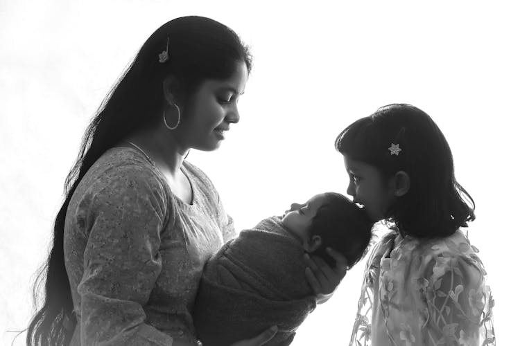 Smiling Mother Holding Baby Near Daughter