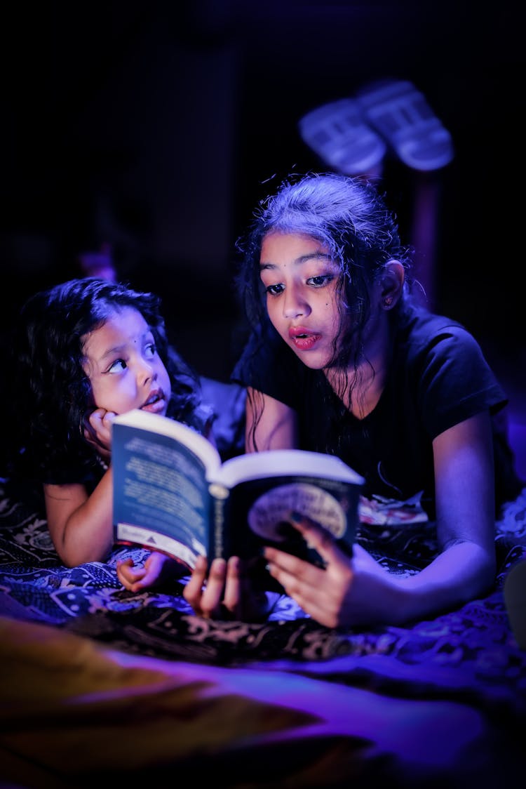 Young Girls Reading A Book In Darkness