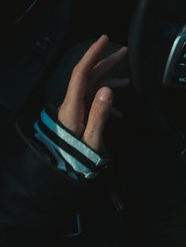 A close-up view of a hand reaching out in a car interior, emphasizing human interaction.