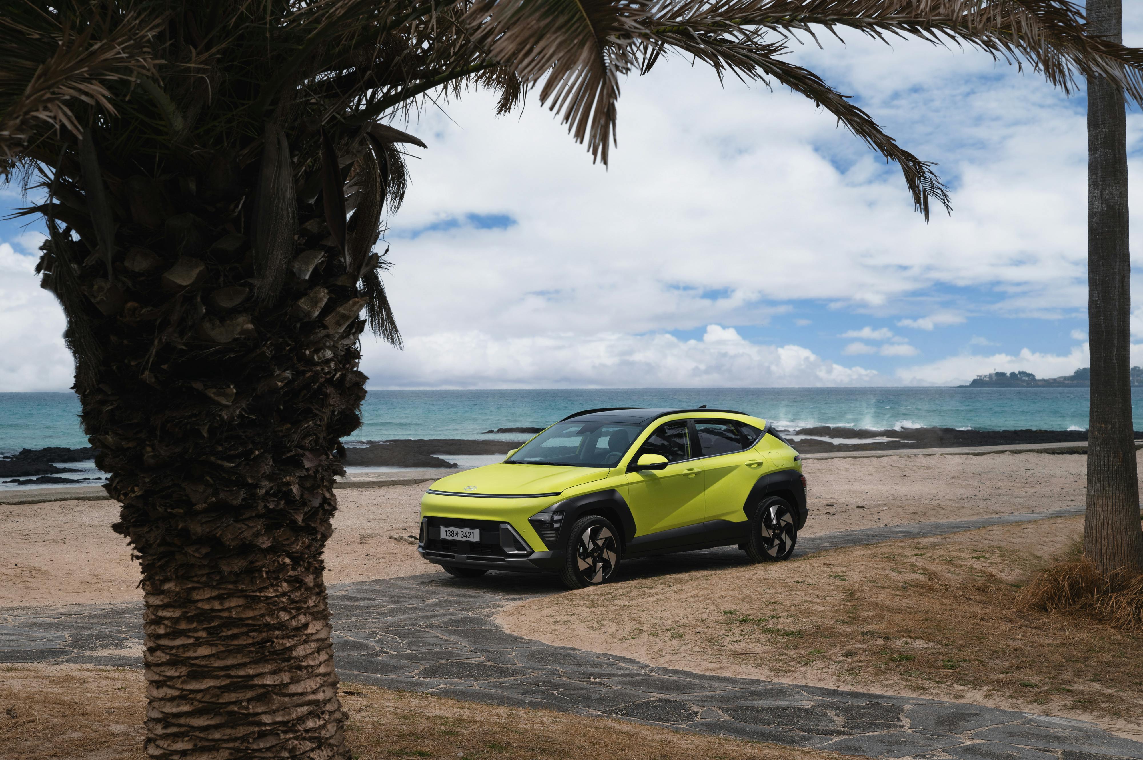 A sleek SUV on a beautiful beach in Jeju City, South Korea, with palm trees and ocean in view.