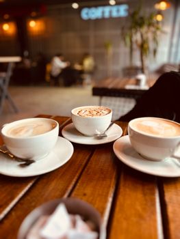 Warm, inviting café scene with three cups of coffee on a wooden table.