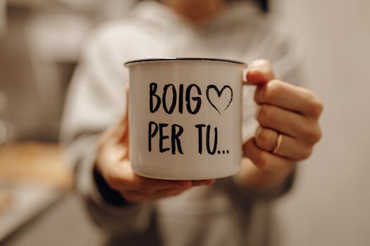 Person holding a white mug with the words 'Boig Per Tu' in cozy indoor setting.