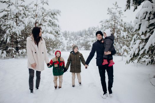 Family enjoying a snowy winter day in the forest, walking and bonding together, capturing joyful moments.