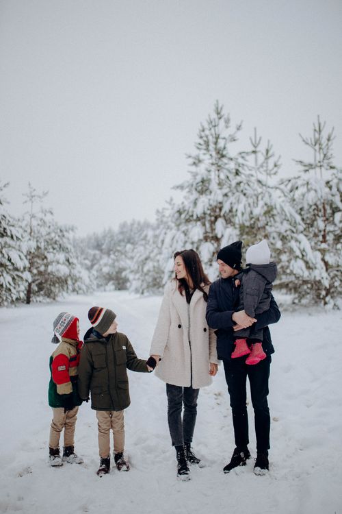 Free Family enjoying a snowy day in a winter forest, bundled up warmly for fun in nature. Stock Photo