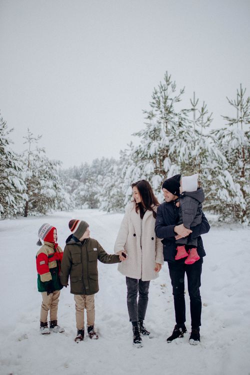 Free A family of five bonding in a snowy forest setting, embracing the winter season. Stock Photo