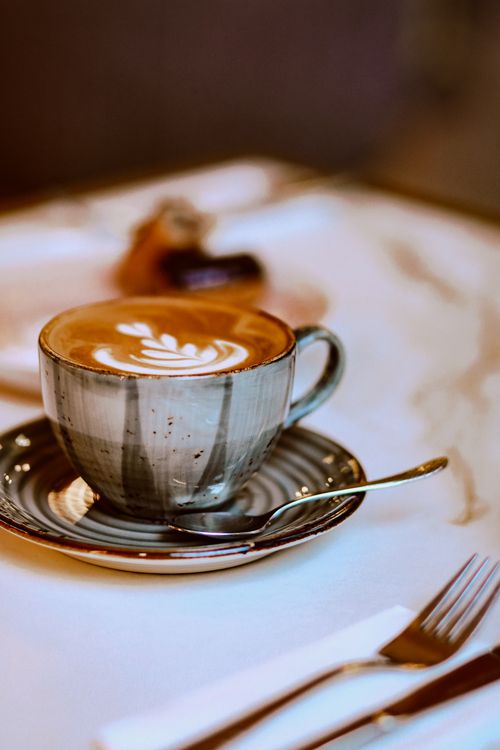 Free Close-up of a coffee cup with latte art, spoon, and saucer in a cafe setting in Baku, Azerbaijan. Stock Photo