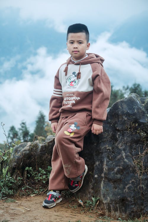 Boy Wearing Overalls Leaning against a Rock