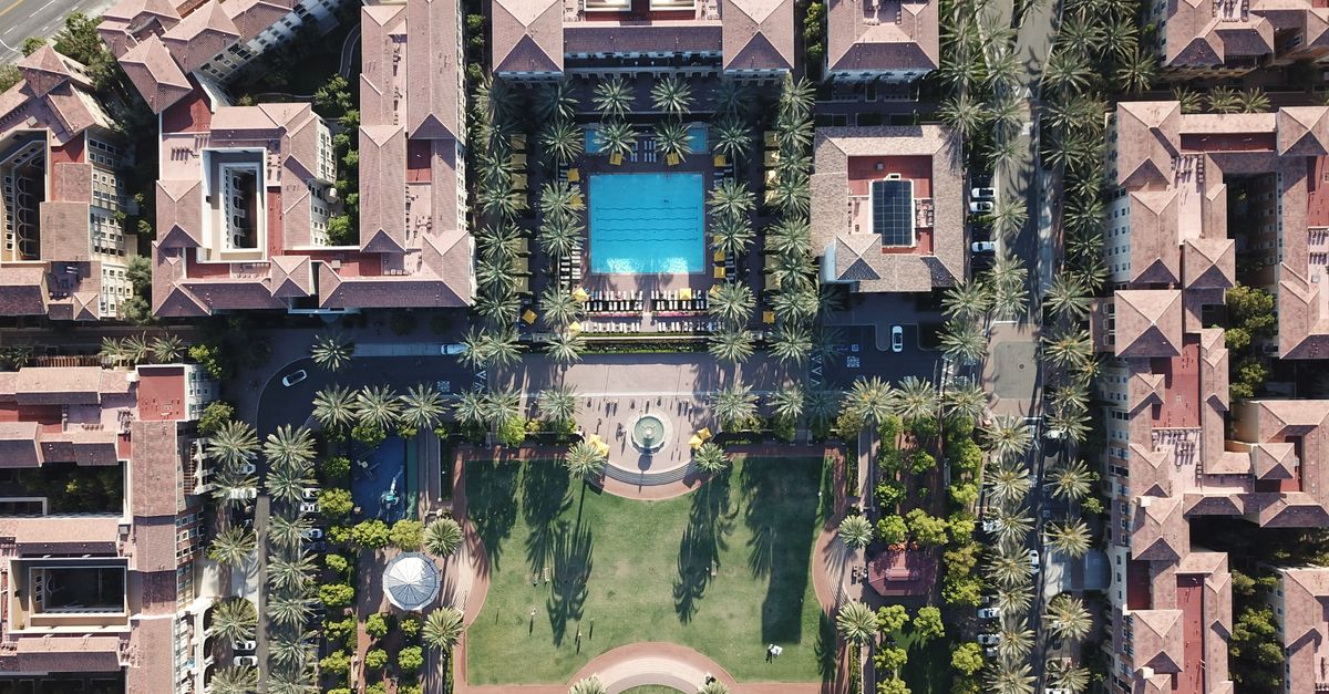 Explore an aerial view of a luxurious residential complex featuring a central swimming pool and lush gardens in Irvine, CA.