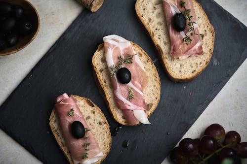 Top View of Bread Slices with Ham and Black Olive on Top 