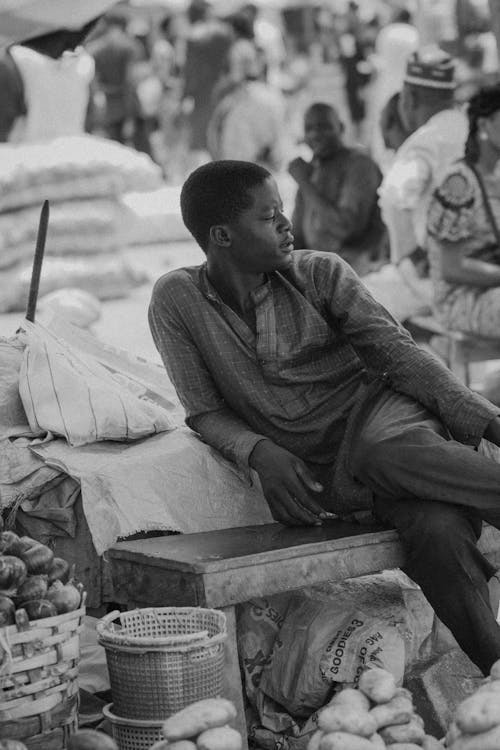 Black Man Sitting on Bench on Street Market