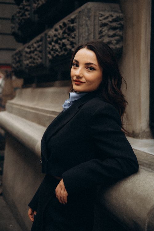 Free Stylish woman in an urban setting, confidently posing against a textured wall. Stock Photo