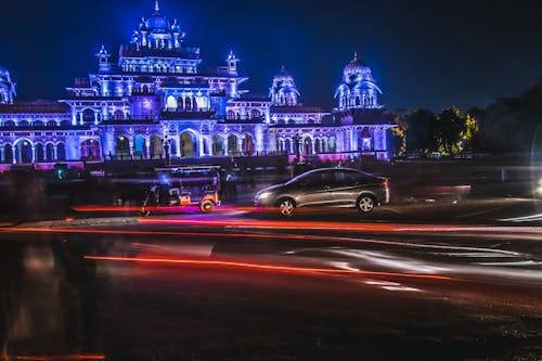 Free Grey Sedan and Red Auto Rickshaw in Front of Purple Mansion Stock Photo