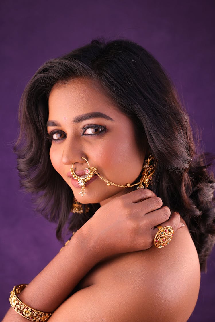 Young Woman In Golden Jewelry Posing In Studio