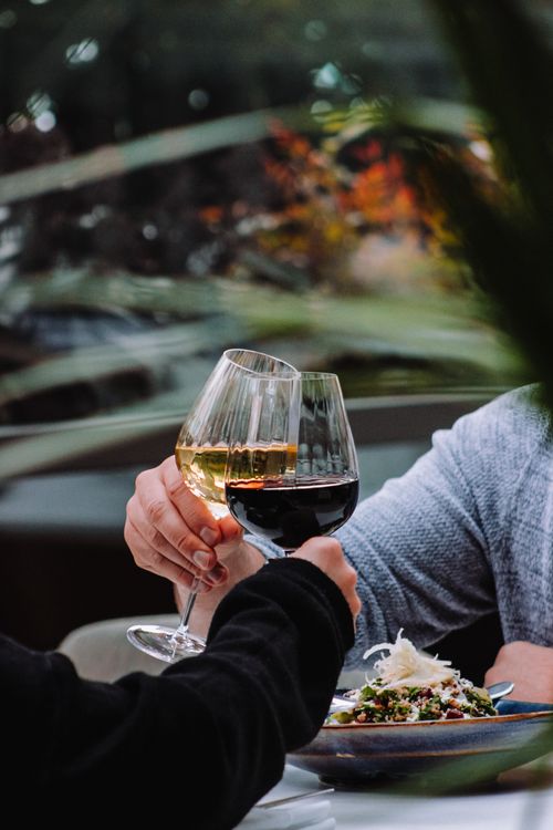 Free Two people toasting with red and white wine glasses over a cozy meal. Stock Photo