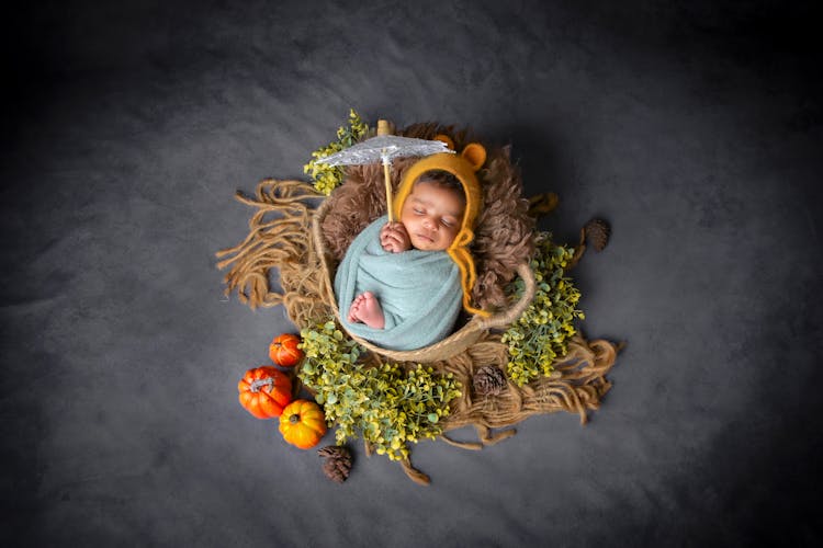 Cute Baby Wrapped In A Towel Sleeping In A Bag Lying On A Beach