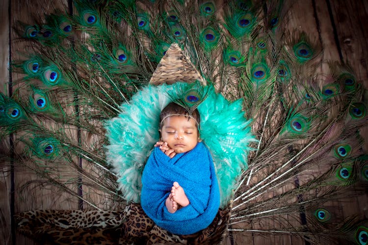 Cute Baby Wrapped In A Towel Sleeping On Peacock Feathers