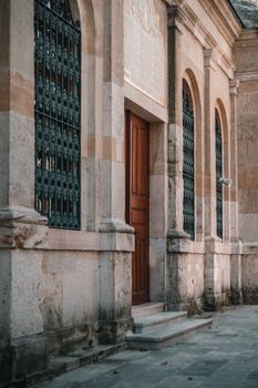 A close-up view of a historic stone church facade featuring elegant arched windows and a wooden entrance.