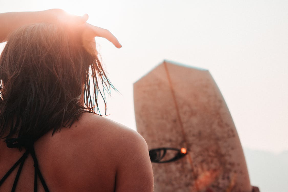 Photo of Woman Standing in Front of a Surfboard