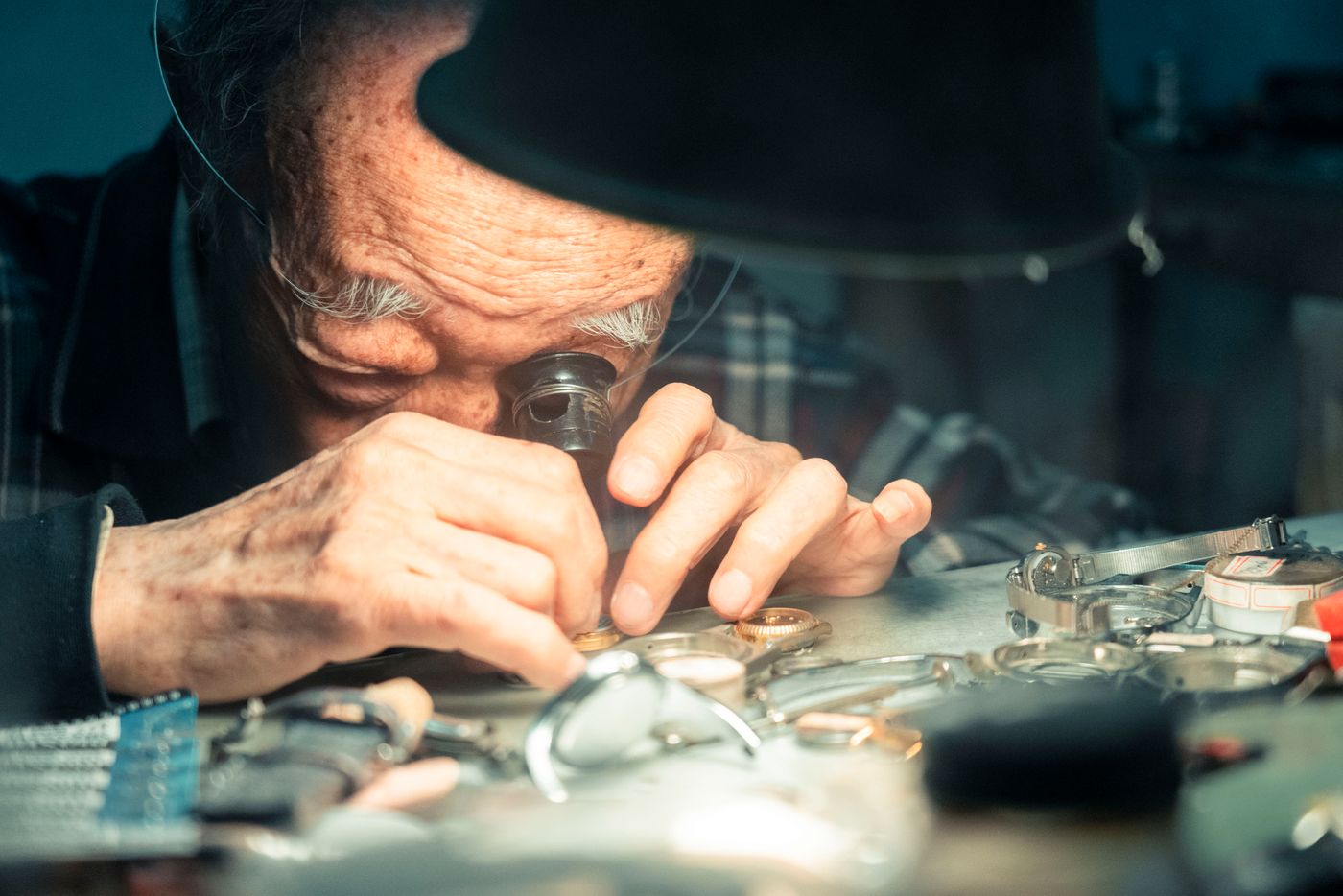 A senior watchmaker examining wristwatches through a loupe at his bench. Photo by Jimmy Liao on Pexels