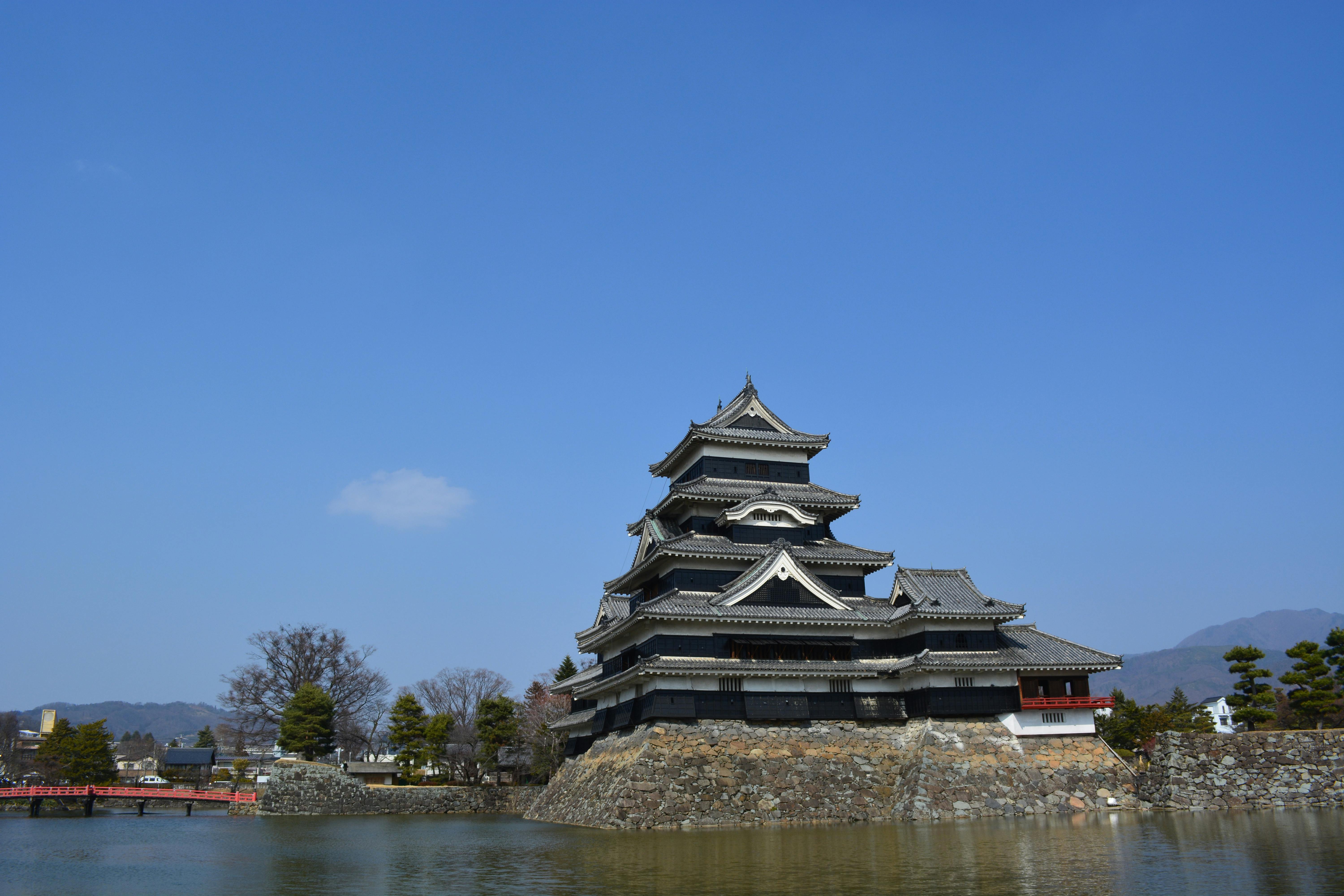 Early morning sunlight illuminating the iconic black Matsumoto Castle with the snow-capped Japanese Alps rising majestically behind