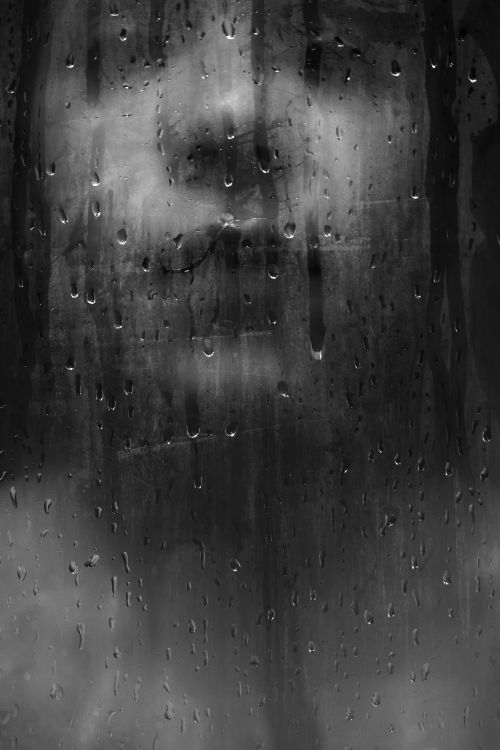 Free A haunting black and white image of a face behind a wet pane of glass. Stock Photo