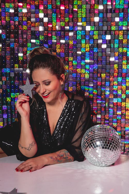Smiling Woman Posing near Disco Ball on Glitter Background