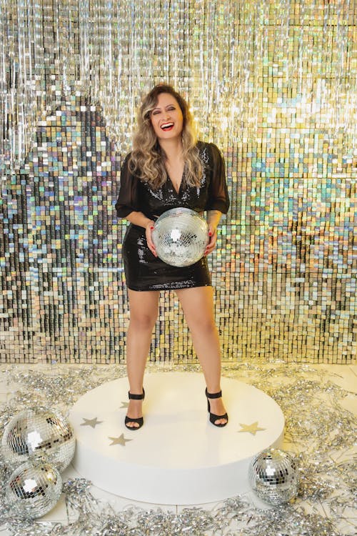Smiling Woman with Disco Ball Posing on Glitter Background