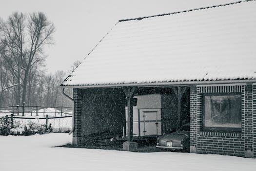 A vintage car parked in a snow-covered German garage during winter, creating a nostalgic scene.