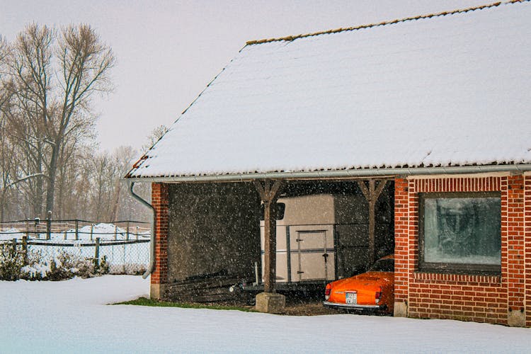 Classic Car In Garage Of Red Brick House In Snowy Winter