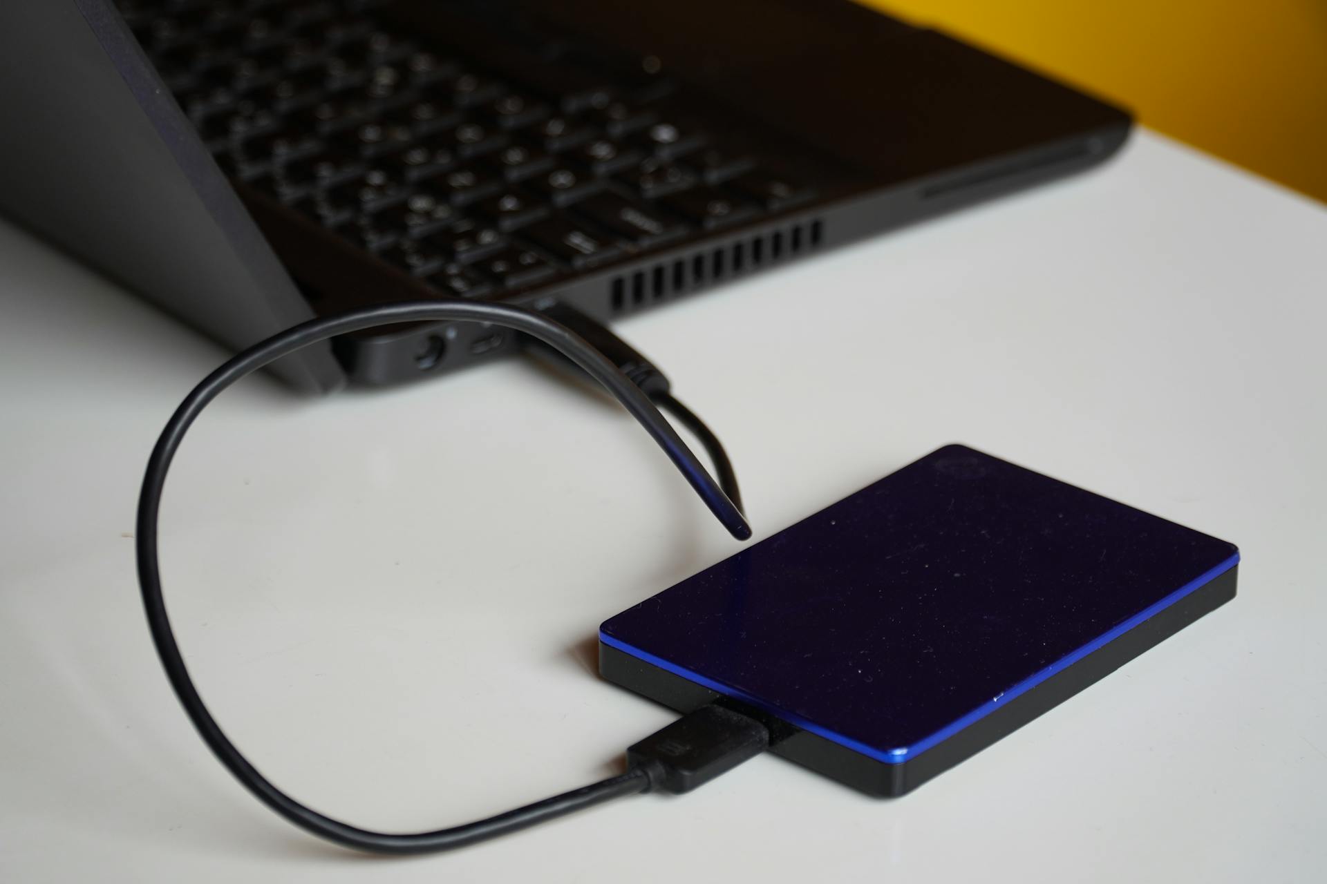 External hard drive connected to a laptop, showcasing portable storage solution.