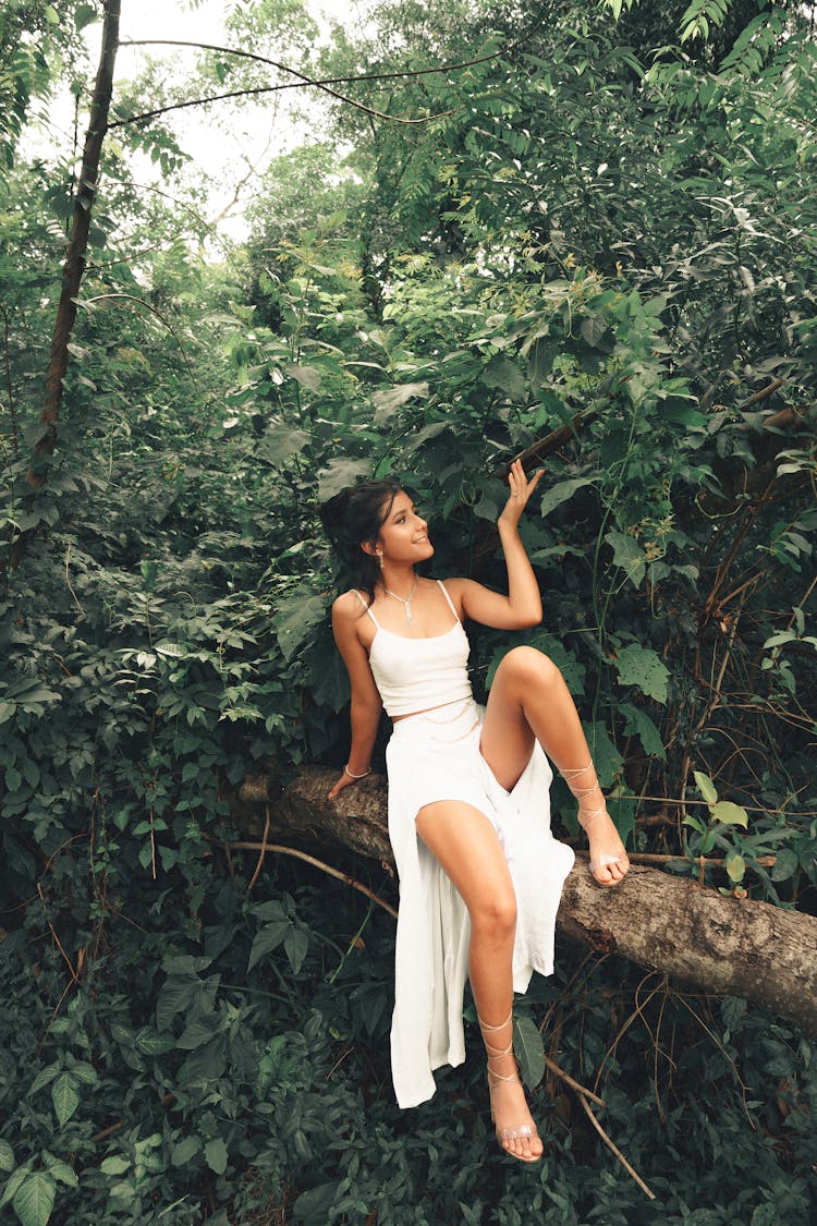 Girl Sitting On Tree Trunk In Green Forest