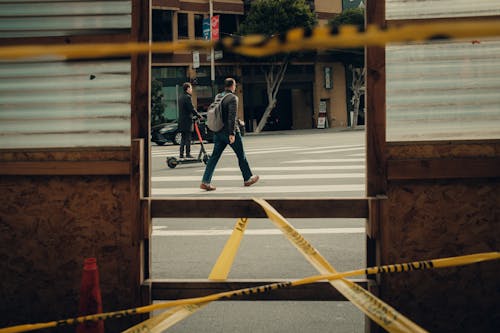 Free A man walking across a street with caution tape Stock Photo