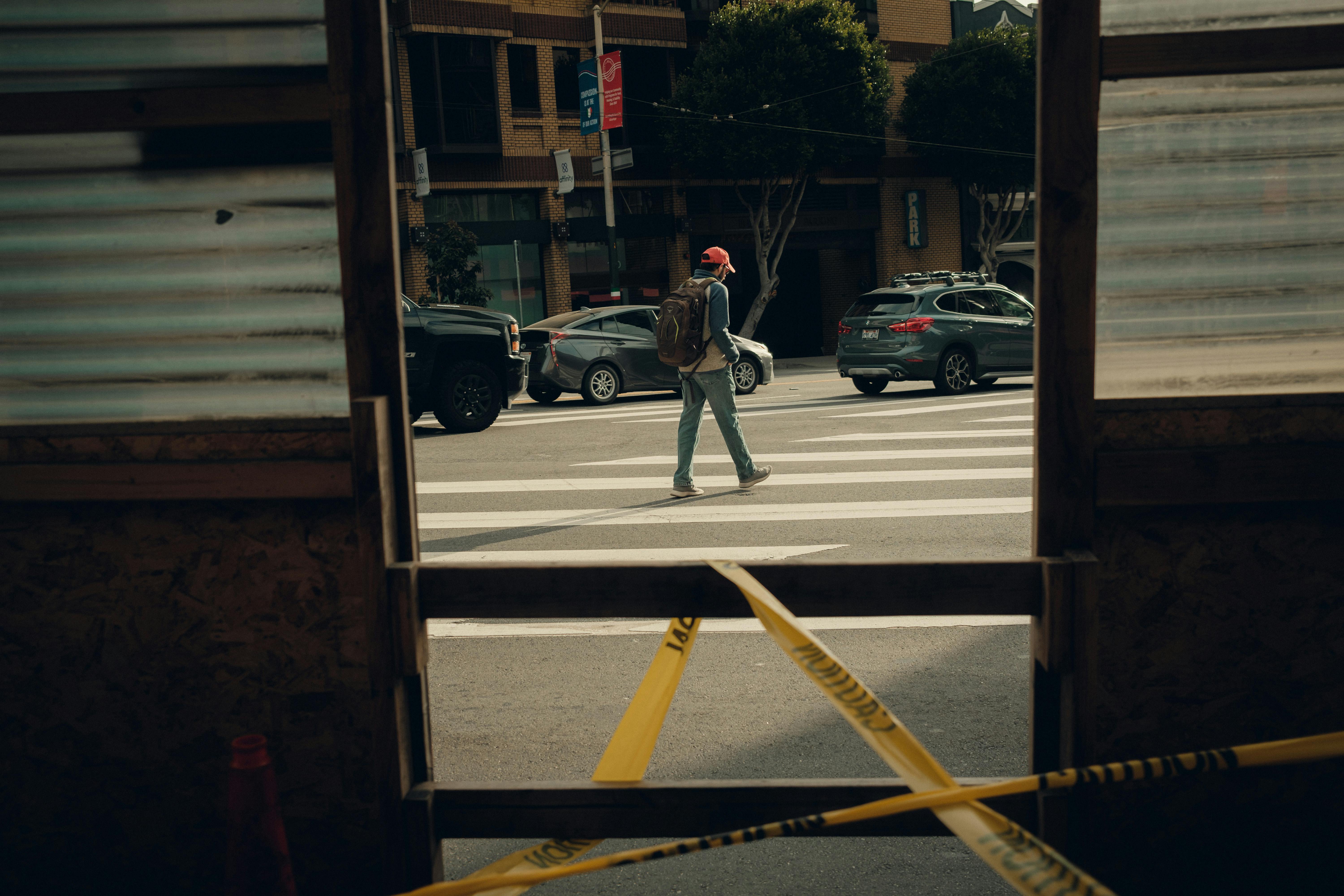 A man walking across a street with a yellow tape