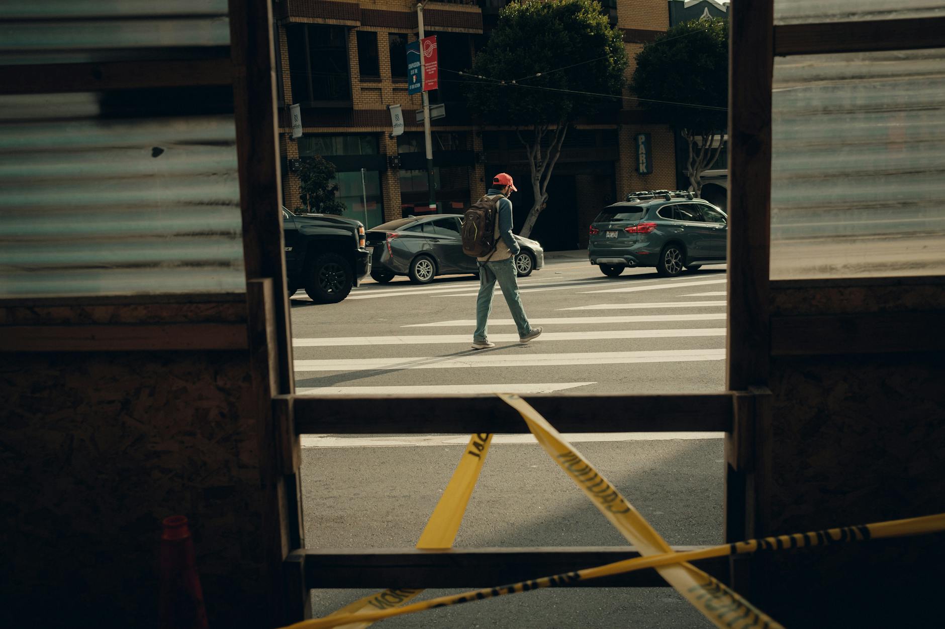 A man walking across a street with a yellow tape