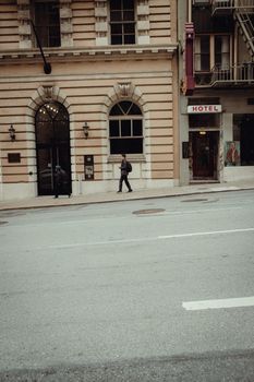 Street view of a city building with pedestrians walking outside a hotel entrance.