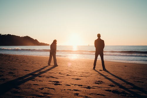 Back View of Woman and Man on Beach at Sunset