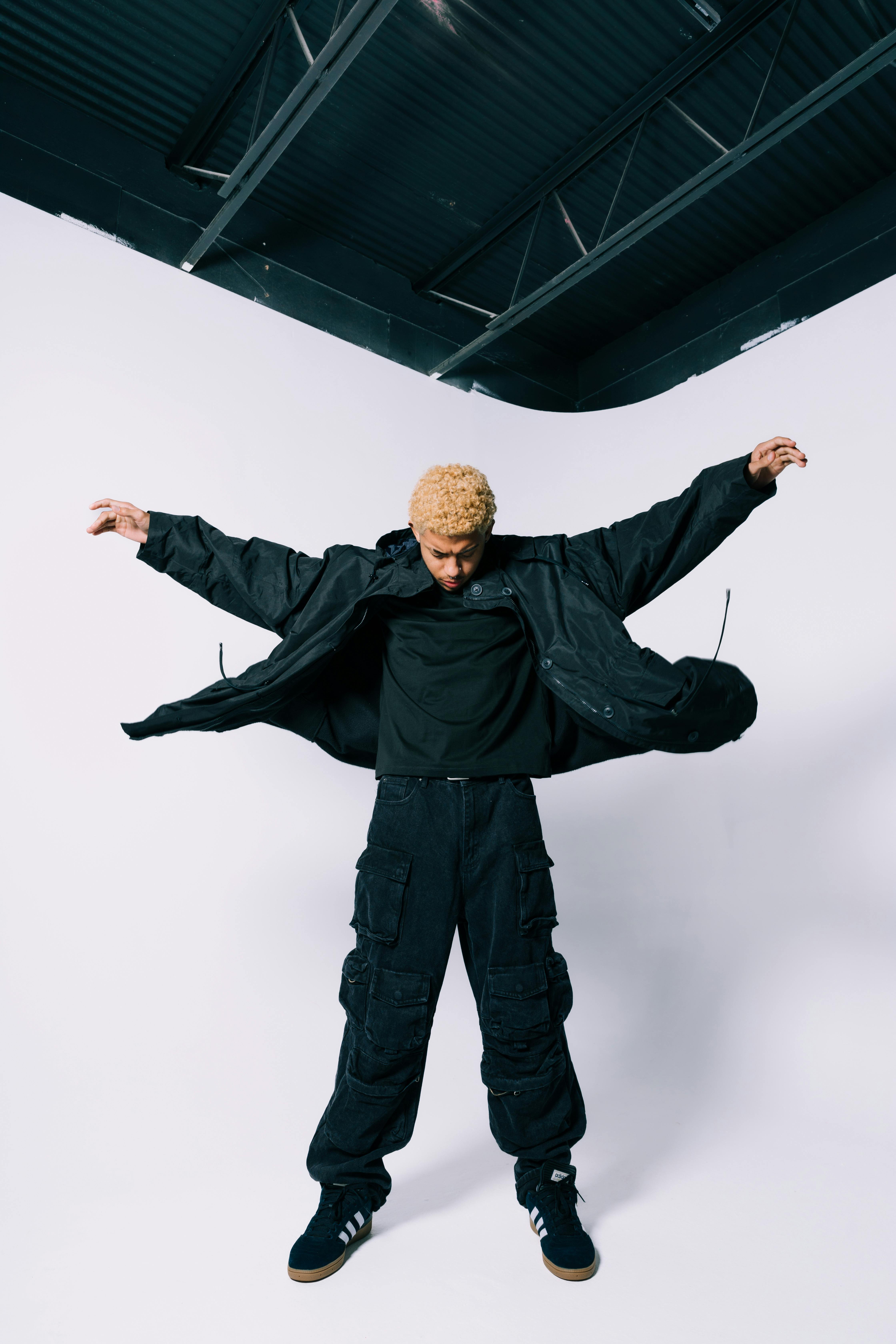 Dynamic studio shot of a man in trendy streetwear and cargo pants striking a pose.