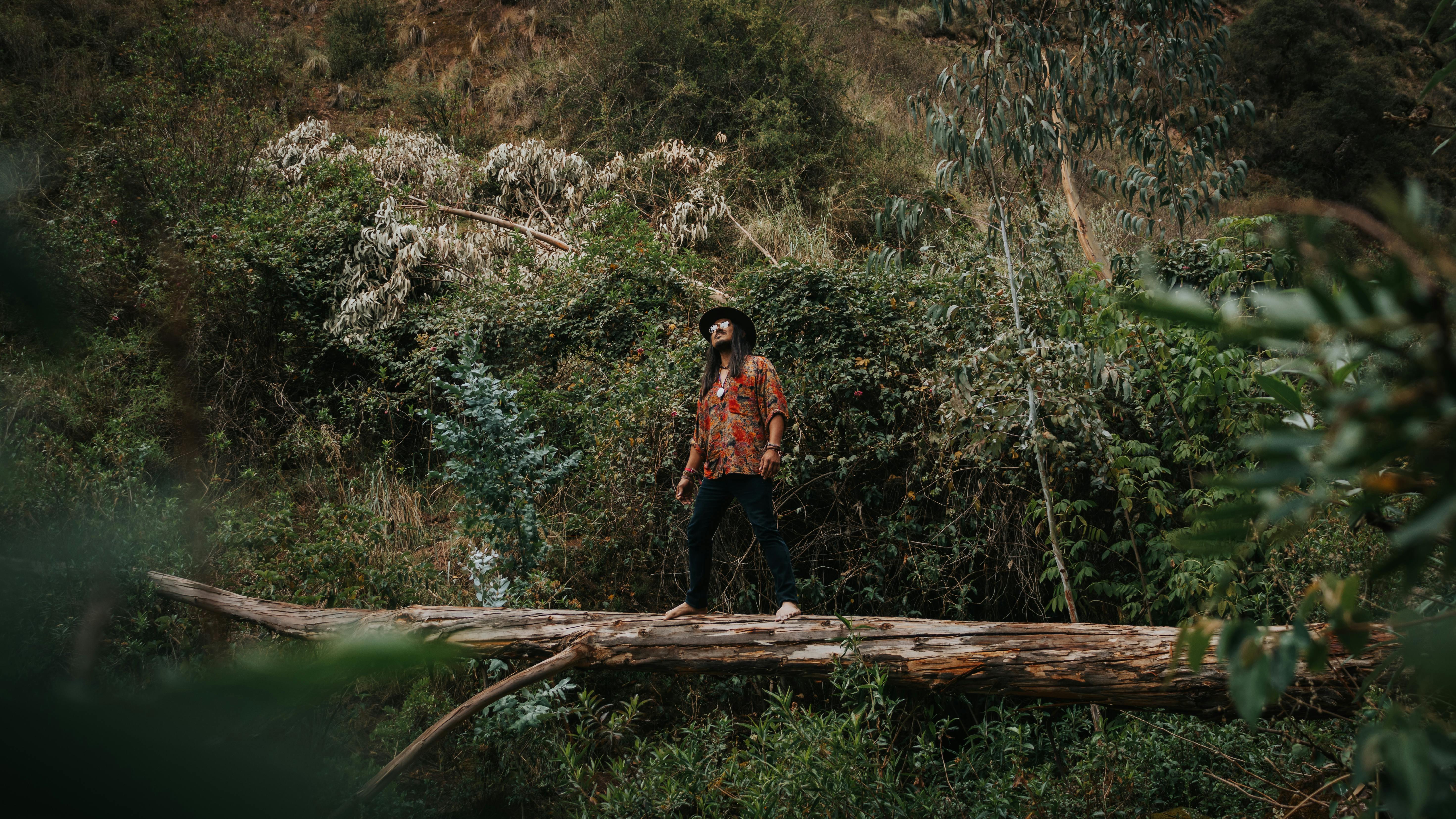 Man standing on a log in a dense forest, embodying nature and escape.