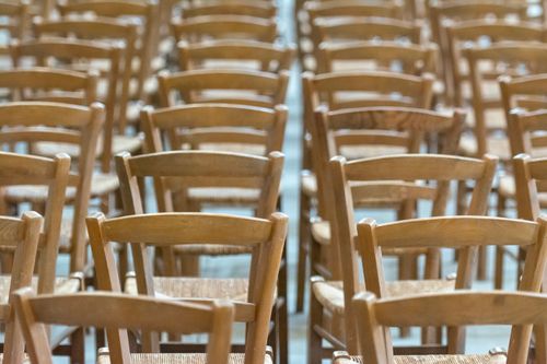 Free A close-up view of empty wooden chairs arranged neatly in rows, creating a serene and organized atmosphere. Stock Photo