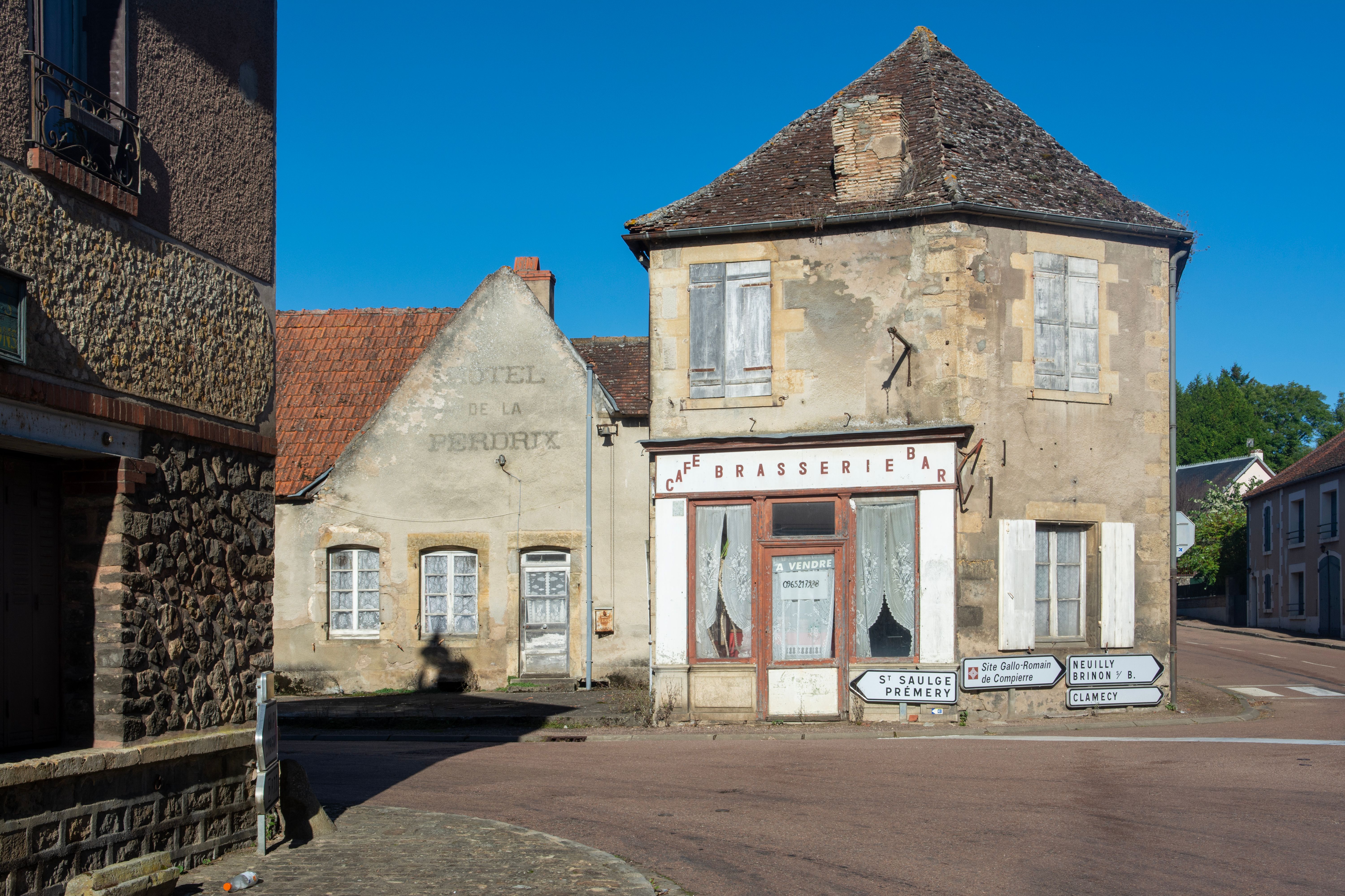 Quaint street view of a rural French town with vintage buildings and signage.