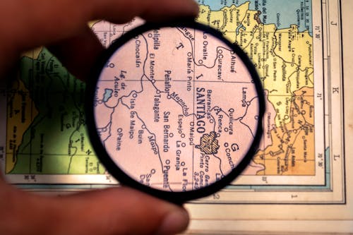 Hand Holding Magnifying Glass over Map
