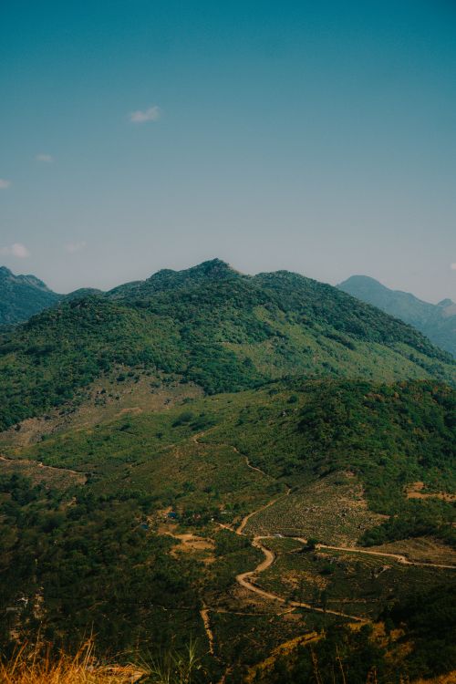 Free Scenic view of a lush green mountain range under a bright blue sky, showcasing natural beauty. Stock Photo