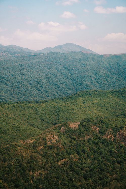 Free A stunning aerial shot capturing lush, green mountain ranges under a blue sky. Stock Photo
